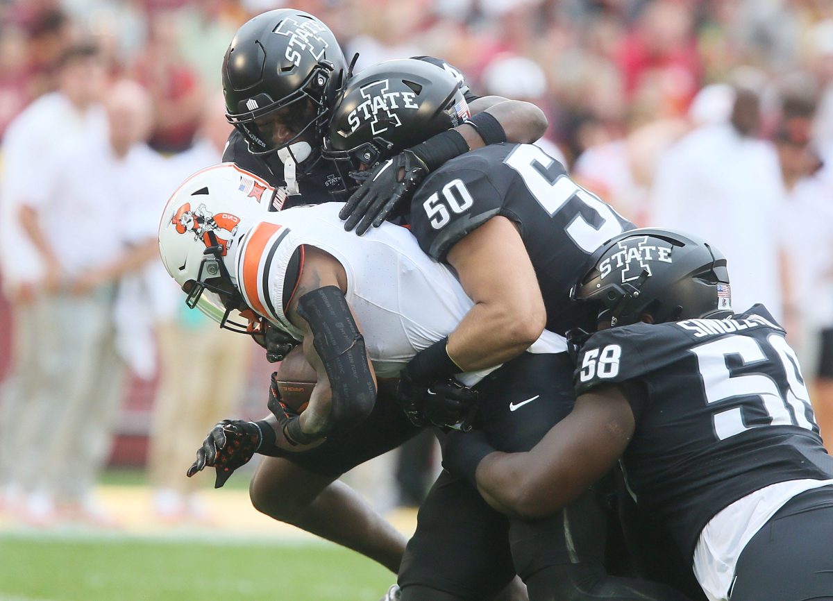 Iowa State Cyclones defensive line J.R. Singleton (58),' linebacker Caleb Bacon (50)t, and defensive back Treyveon McGee (24) takes down Oklahoma State Cowboys' running back Ollie Gordon II (0) during the first quarter of an NCAA college football game at Jack Trice Stadium on Saturday, Sept. 23, 2023, in Ames, Iowa.