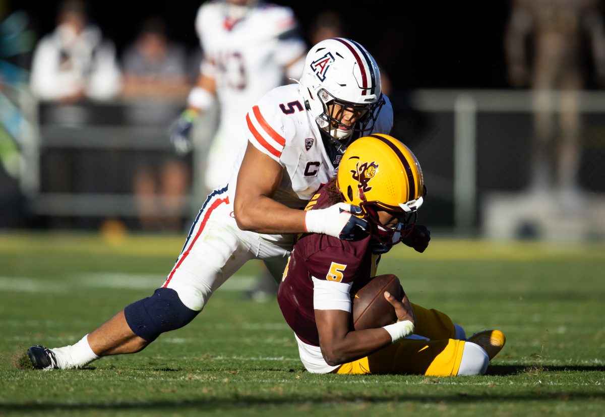 Nov 25, 2023; Tempe, Arizona, USA; Arizona Wildcats linebacker Jacob Manu (top) sacks Arizona State Sun Devils quarterback Jaden Rashada in the second half of the Territorial Cup at Mountain America Stadium. Mandatory Credit: Mark J. Rebilas-USA TODAY Sports