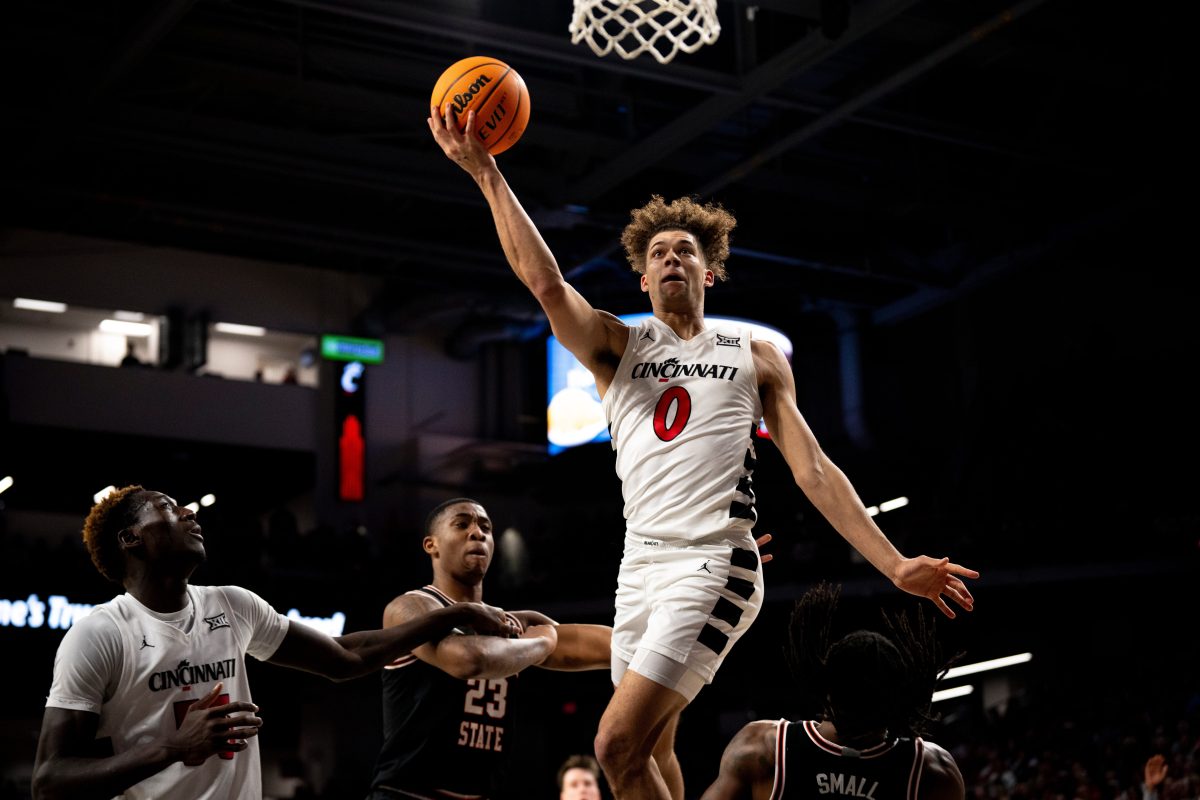 Cincinnati Bearcats guard Dan Skillings Jr. (0) hits a layup around Oklahoma State Cowboys guard Javon Small (12) and Oklahoma State Cowboys center Brandon Garrison (23) as Cincinnati Bearcats forward Aziz Bandaogo (55) looks on in the first half of the NCAA basketball game between Cincinnati Bearcats and Oklahoma State Cowboys at Fifth Third Arena in Cincinnati on Wednesday, Feb. 21, 2024.